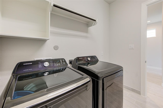 clothes washing area with laundry area, light wood-style flooring, independent washer and dryer, and baseboards