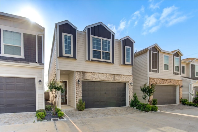 view of property with board and batten siding, an attached garage, driveway, and brick siding