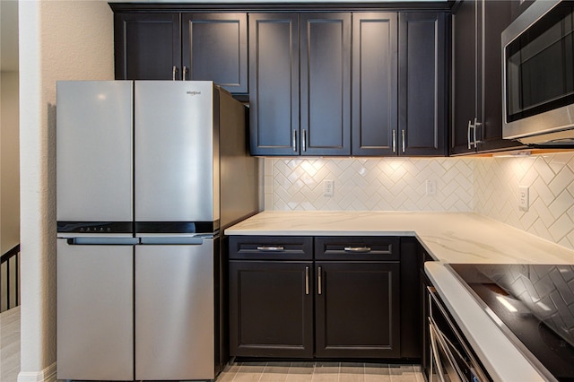 kitchen featuring stainless steel appliances, light stone countertops, and decorative backsplash