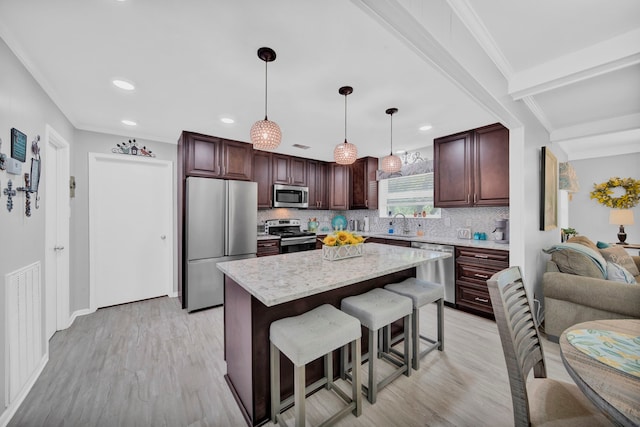 29133 E Lake Dr, Hempstead, TX 77445 - kitchen featuring light wood-style floors, appliances with stainless steel finishes, a breakfast bar area, and tasteful backsplash