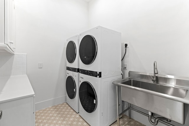11365 Beachside Dr, Galveston, TX 77554 - clothes washing area featuring stacked washing machine and dryer, cabinet space, light flooring, and baseboards