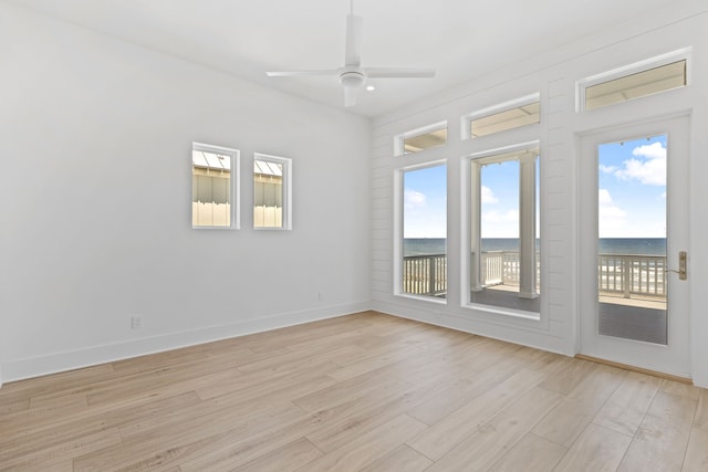 11365 Beachside Dr, Galveston, TX 77554 - empty room featuring light wood-type flooring, a ceiling fan, a water view, and baseboards