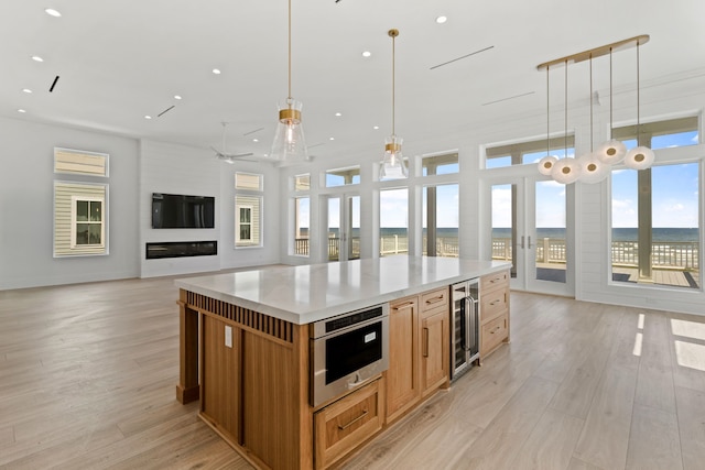 11365 Beachside Dr, Galveston, TX 77554 - kitchen with beverage cooler, a spacious island, recessed lighting, light wood-type flooring, and pendant lighting
