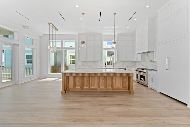 11365 Beachside Dr, Galveston, TX 77554 - kitchen with double oven range, light wood-type flooring, a large island, light countertops, and decorative backsplash