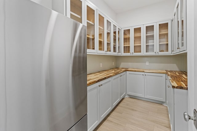 11365 Beachside Dr, Galveston, TX 77554 - kitchen featuring wood counters, freestanding refrigerator, glass insert cabinets, and light wood finished floors