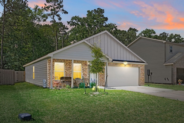 view of front facade with board and batten siding, a lawn, a garage, brick siding, and concrete driveway