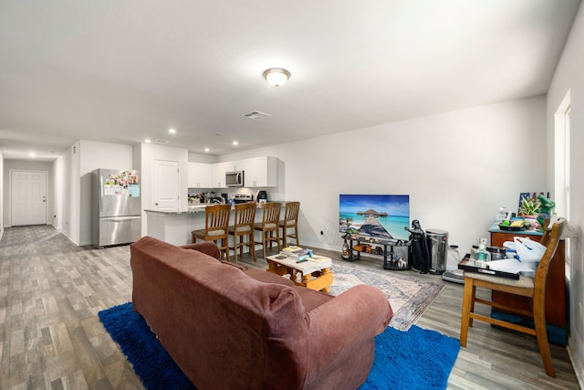living area featuring visible vents, recessed lighting, light wood-style floors, and baseboards