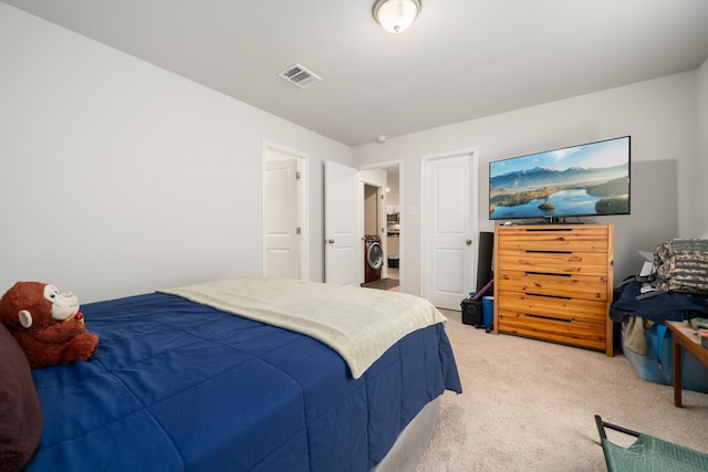 bedroom with washer / dryer, light colored carpet, and visible vents