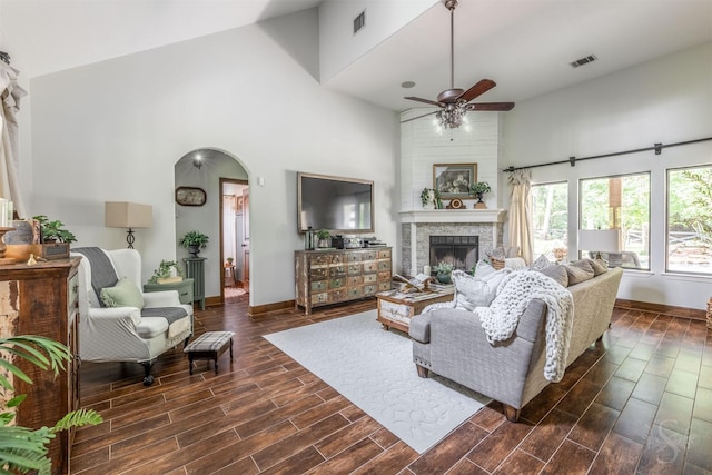 living room with visible vents, ceiling fan, a high ceiling, and a fireplace