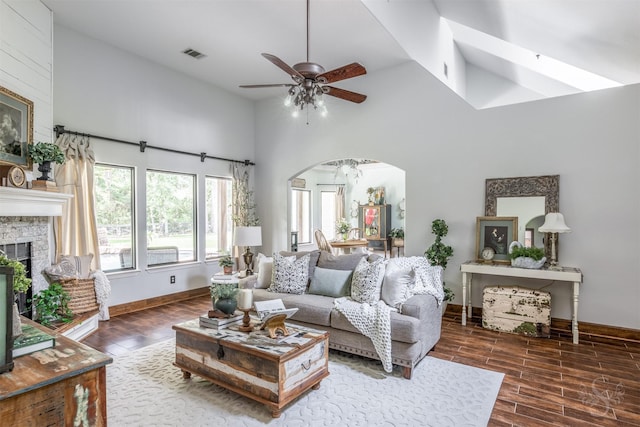living area featuring a towering ceiling, a ceiling fan, wood finished floors, and visible vents