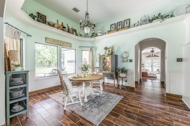 dining room featuring visible vents, arched walkways, baseboards, dark wood-style floors, and a high ceiling
