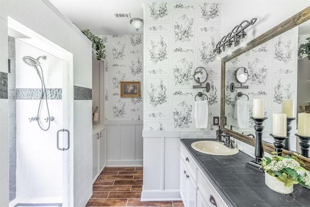 full bathroom with vanity, a stall shower, wood finished floors, and visible vents