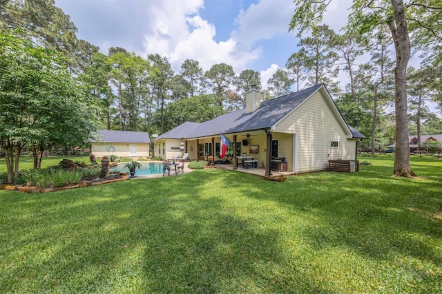 back of property with a yard, a patio, a ceiling fan, and a chimney