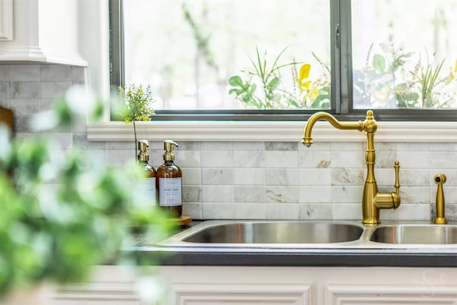 interior details featuring white cabinetry, a sink, and tasteful backsplash