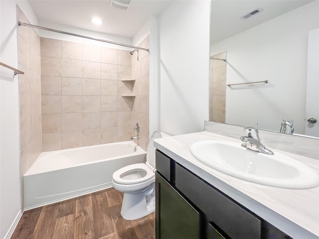 bathroom with visible vents, vanity, wood finished floors, toilet, and shower / tub combination
