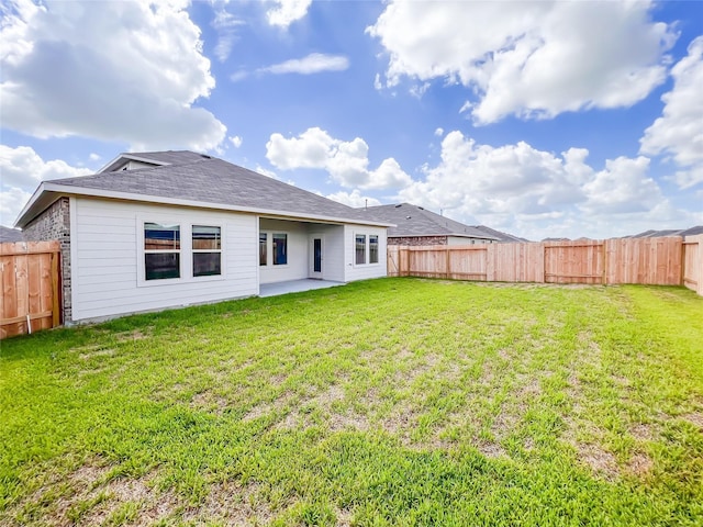 rear view of house with a lawn and a fenced backyard