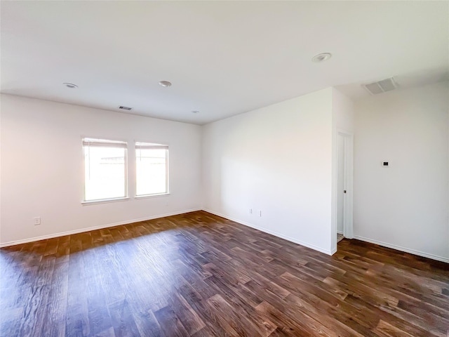 empty room featuring baseboards, visible vents, and dark wood-type flooring