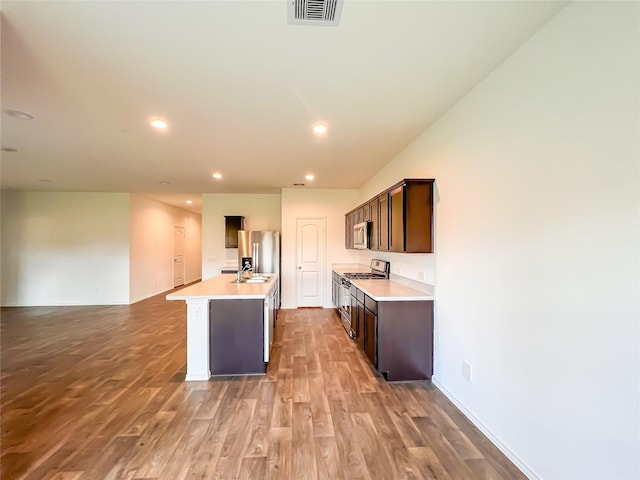 kitchen featuring a kitchen island with sink, visible vents, appliances with stainless steel finishes, wood finished floors, and dark brown cabinets