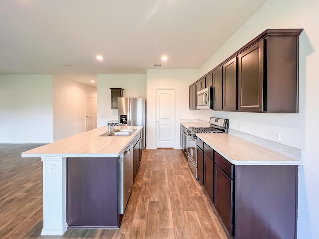 kitchen with light wood-type flooring, light countertops, dark brown cabinets, and stainless steel appliances