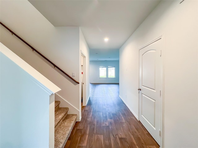 hallway featuring baseboards, dark wood-style floors, and stairway