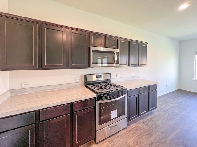 kitchen with light wood-style floors, light countertops, baseboards, and stainless steel appliances