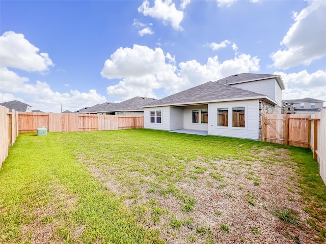 rear view of house with a lawn and a fenced backyard