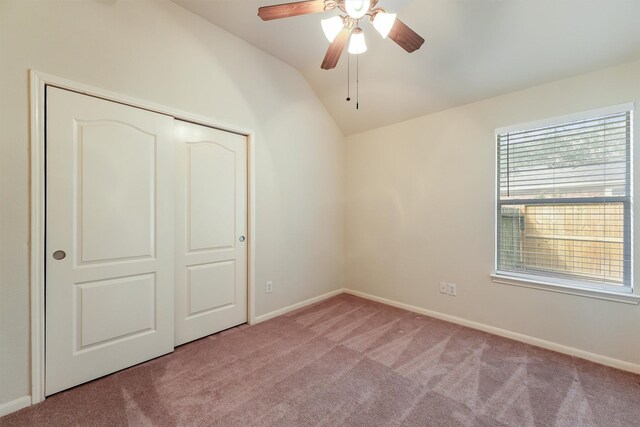 unfurnished bedroom with a ceiling fan, baseboards, a closet, lofted ceiling, and carpet flooring