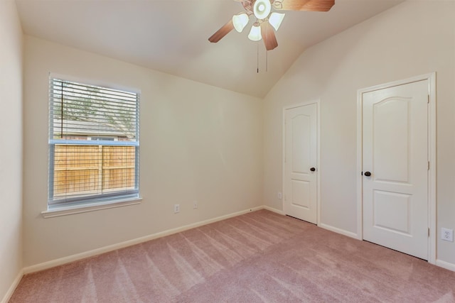 unfurnished bedroom featuring a ceiling fan, baseboards, light colored carpet, and vaulted ceiling