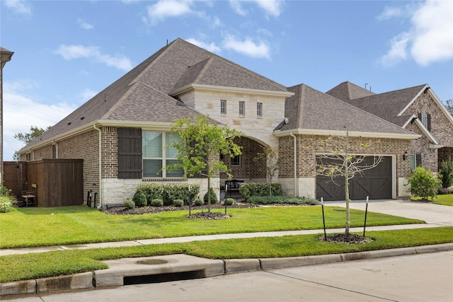 1017 Goose Creek St, Webster, TX 77598 - french country style house featuring roof with shingles, an attached garage, and brick siding