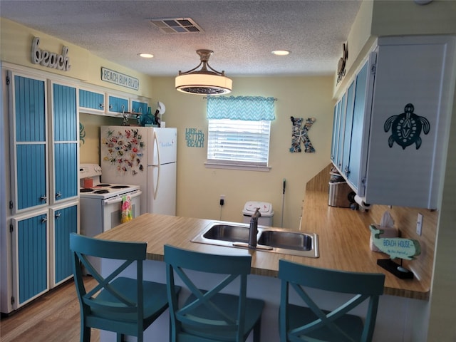 16607 Henry Morgan Rd, Jamaica Beach, TX 77554 - kitchen with a textured ceiling, visible vents, wood finished floors, a sink, and white appliances