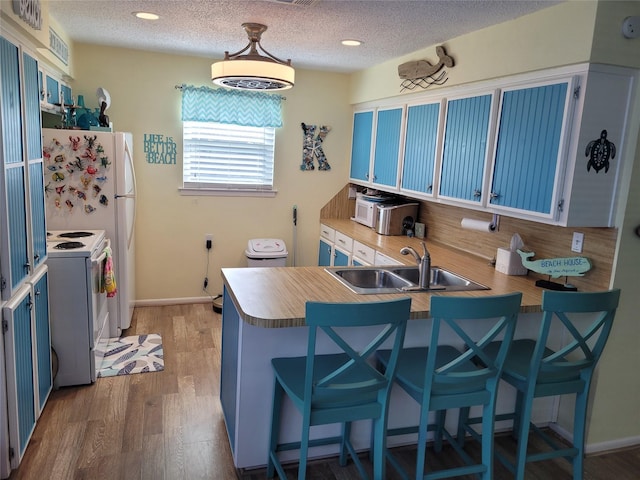16607 Henry Morgan Rd, Jamaica Beach, TX 77554 - kitchen featuring white electric range oven, a sink, a breakfast bar area, blue cabinetry, and a peninsula