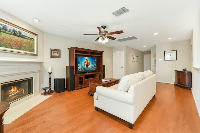 living room featuring ceiling fan, a glass covered fireplace, recessed lighting, light wood-type flooring, and visible vents