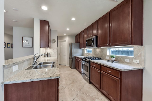 kitchen featuring decorative backsplash, a peninsula, light tile patterned flooring, a sink, and appliances with stainless steel finishes