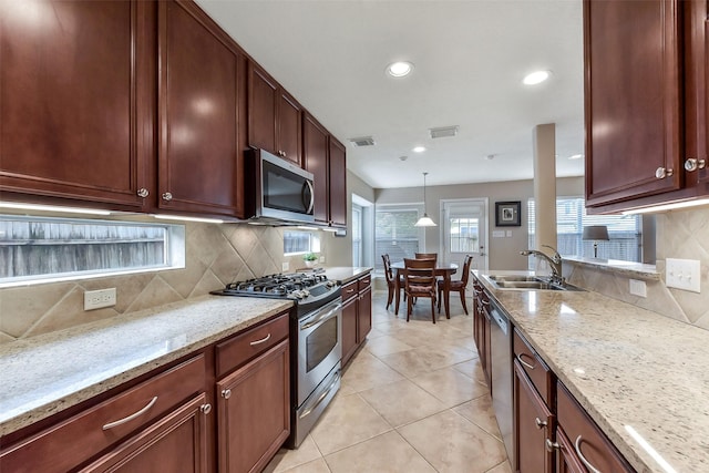 kitchen with stainless steel appliances, visible vents, decorative backsplash, and a sink