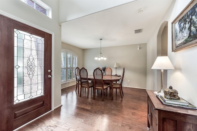 entrance foyer with visible vents, arched walkways, wood finished floors, and a notable chandelier
