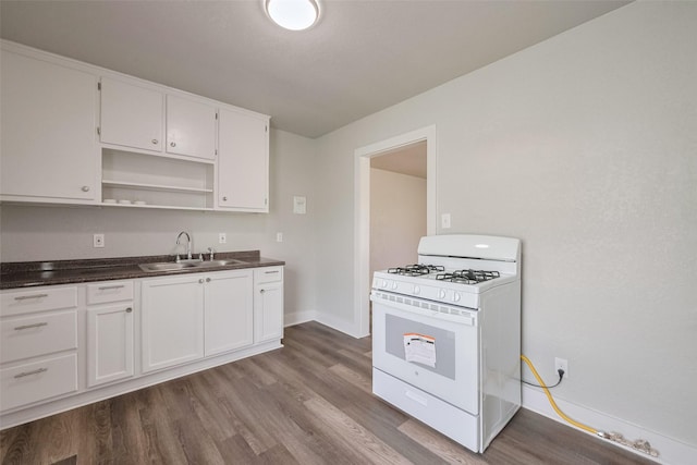 kitchen with open shelves, dark countertops, gas range gas stove, dark wood-style floors, and a sink