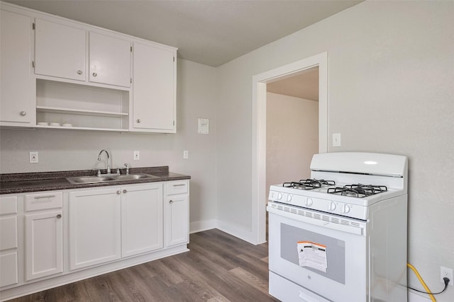 kitchen with white gas range, dark countertops, a sink, and dark wood-type flooring