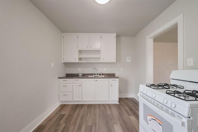 kitchen with baseboards, a sink, light wood-style flooring, and white gas range