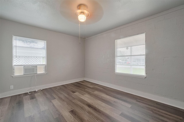 spare room featuring baseboards, a ceiling fan, wood finished floors, and cooling unit