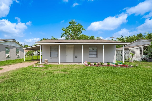 view of front facade featuring an attached carport, driveway, a front yard, and concrete block siding