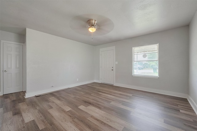empty room with baseboards, ceiling fan, and wood finished floors