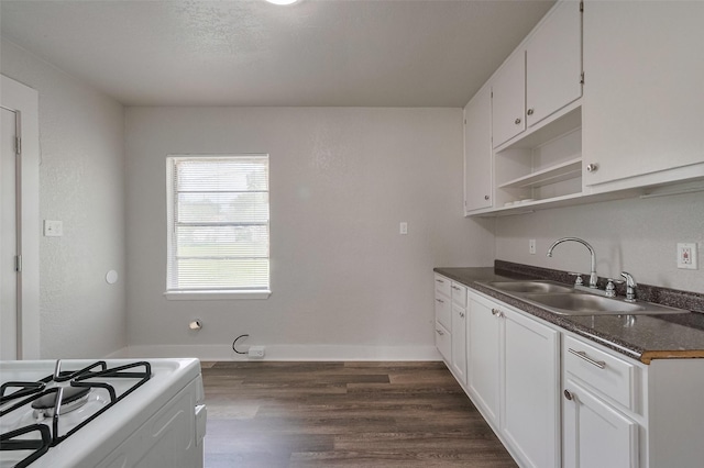 kitchen with open shelves, dark countertops, dark wood-style floors, white cabinets, and a sink