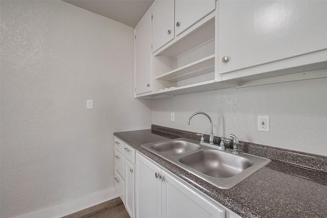 kitchen featuring white cabinetry, open shelves, dark countertops, and a sink