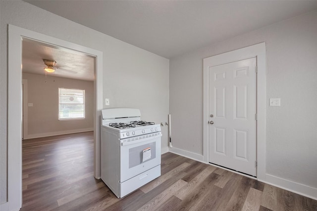 kitchen with baseboards, ceiling fan, white gas stove, and wood finished floors