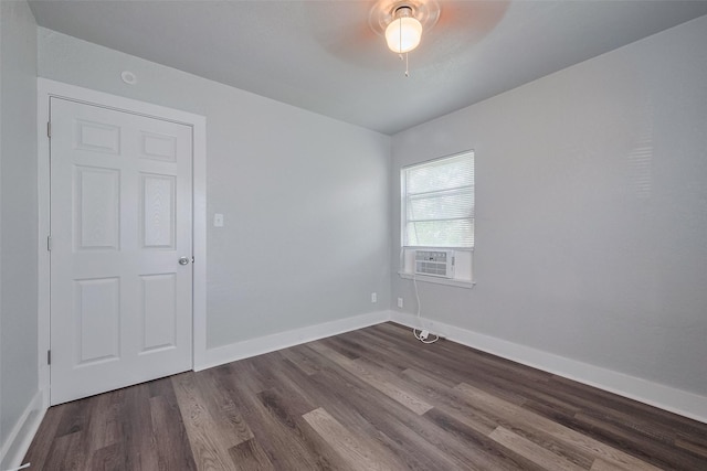empty room with dark wood-style flooring, a ceiling fan, baseboards, and cooling unit