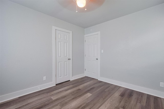 spare room featuring baseboards, a ceiling fan, and dark wood-style flooring