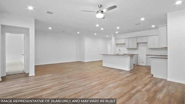 kitchen featuring visible vents, a ceiling fan, light wood-style floors, and open floor plan