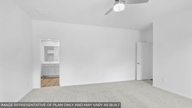 empty room with carpet floors, ceiling fan, a sink, and baseboards