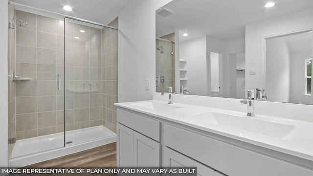 bathroom featuring a stall shower, recessed lighting, a sink, and wood finished floors
