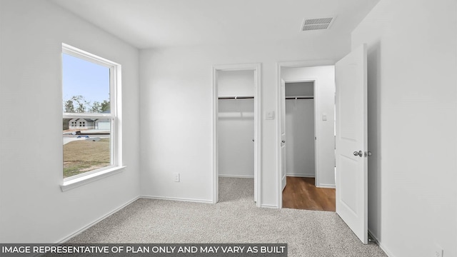 unfurnished bedroom with baseboards, visible vents, a spacious closet, and carpet
